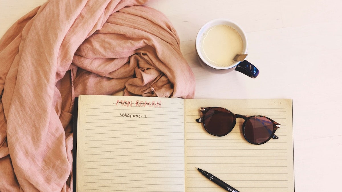 ballpoint pen and sunglasses on opened notebook